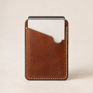 Chestnut leather vertical card holder with three cards visible above an asymmetrical sloped front pocket and cream saddle stitching