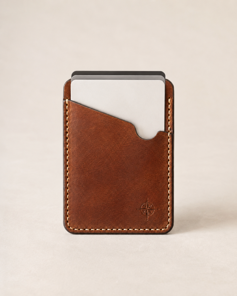 Chestnut leather vertical card holder with three cards visible above an asymmetrical sloped front pocket and cream saddle stitching.